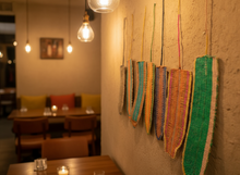 Load image into Gallery viewer, Colorful woven shoes hanging against a wall in a restaurant.