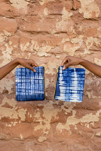 Load image into Gallery viewer, Two hands holding blue tie-dye fabric against an adobe wall background