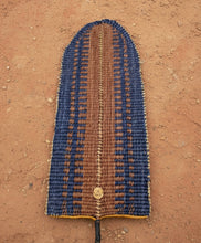 Load image into Gallery viewer, Woven blue and spice orange linear pattern on banana leaf basket laying on a dirt floor