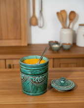 Carregar imagem no visualizador da galeria, Green ceramic jar with lid on a wooden surface, containing yellow powder.