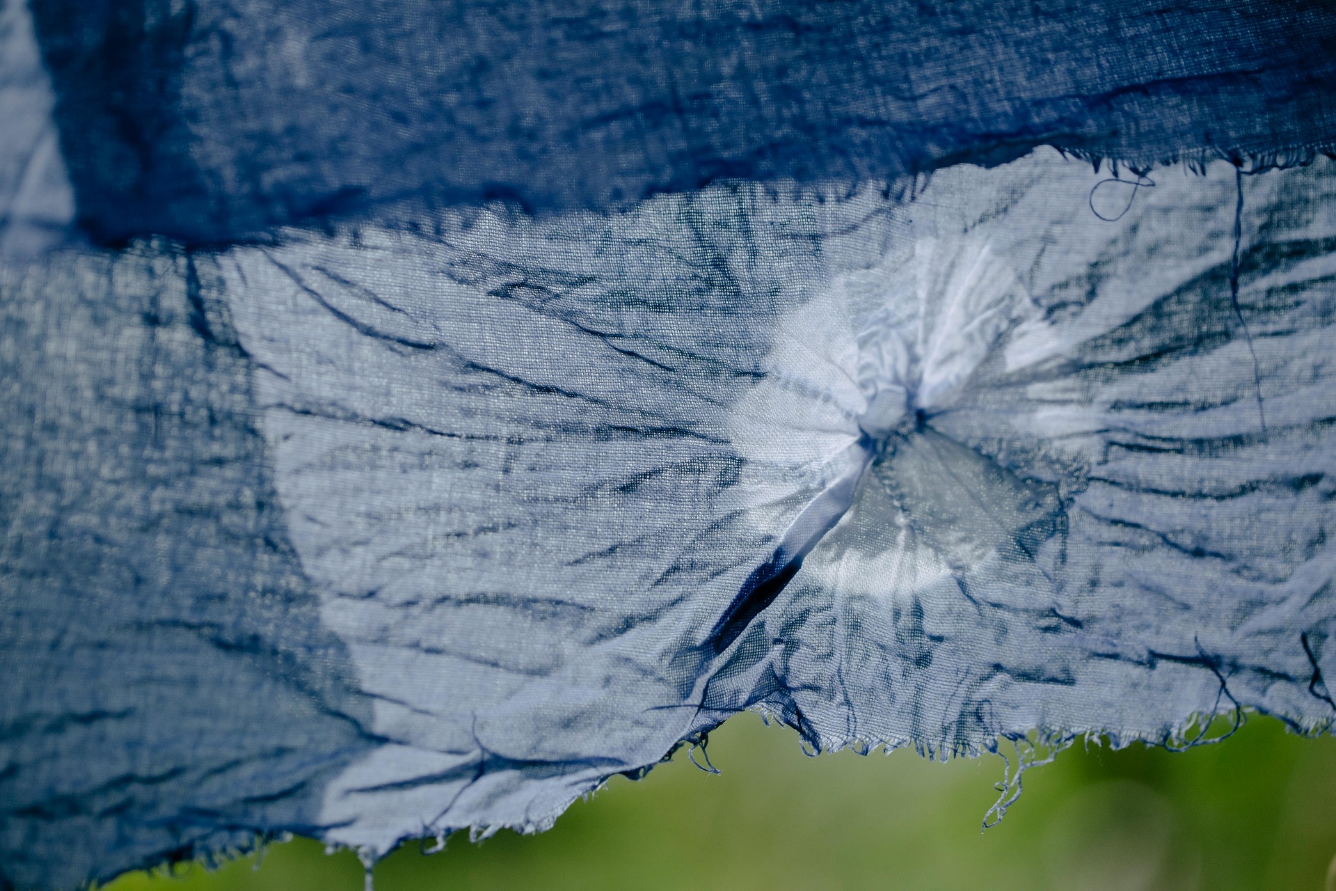 Close-up of indigo tie & dye fabric showing intricate hand-bound resist patterns.