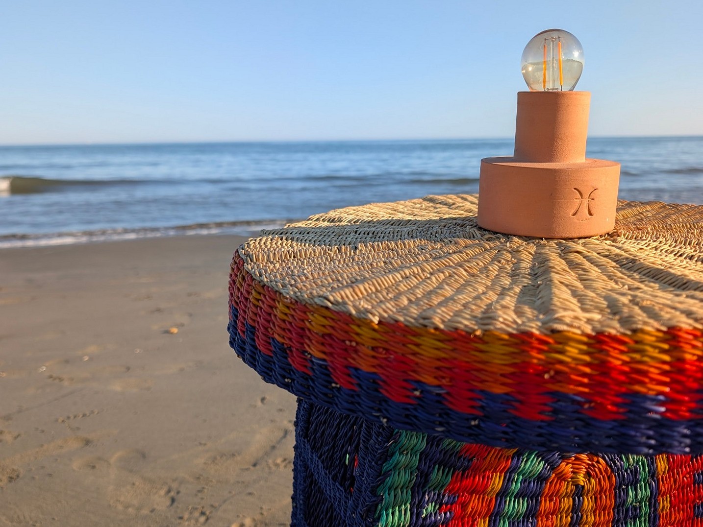 Sahra lamp resting on a handwoven smock rug by the sea
