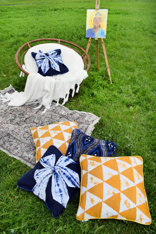 African handmade batik cushions and indigo textiles displayed outdoors on the grass.
