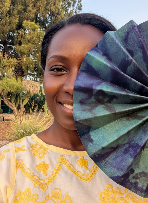 African woman partially covering her face with a fan