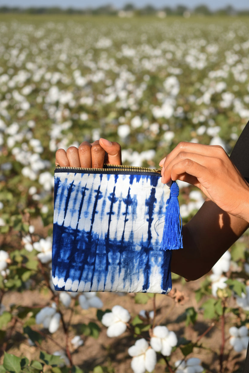Blue and white small tie-dye clutch held by a person against a cotton field background