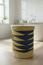 Cargar imagen en el visor de la galería, Woven laundry basket with blue and yellow pattern in a bathroom setting
