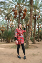 Load image into Gallery viewer, Girl wearing a red and green tie dye kimono surrounded by palmtrees 
