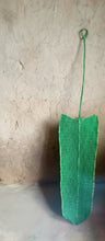 Load image into Gallery viewer, Green woven leaf resting against a textured wall.
