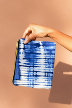 Carregar imagem no visualizador da galeria, Hand holding a blue and white patterned  tie-dye clutch against an adobe color background
