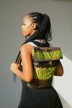 Load image into Gallery viewer, Woman with a green and brown patterned backpack against a leafy background
