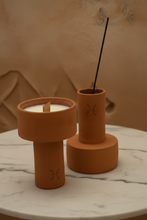 Cargar imagen en el visor de la galería, Two terracotta incense holders with a candle and incense stick on a marble surface.
