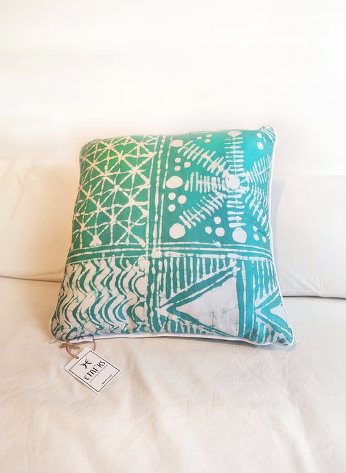 A cushion cover with a geometric Yoruba Adire pattern in turquoise and white colors, featuring a white piping detail.