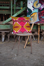 Load image into Gallery viewer,  yellow wax print cushion on an old chair, with farming machinery behind and an abstract painting on a tripod
